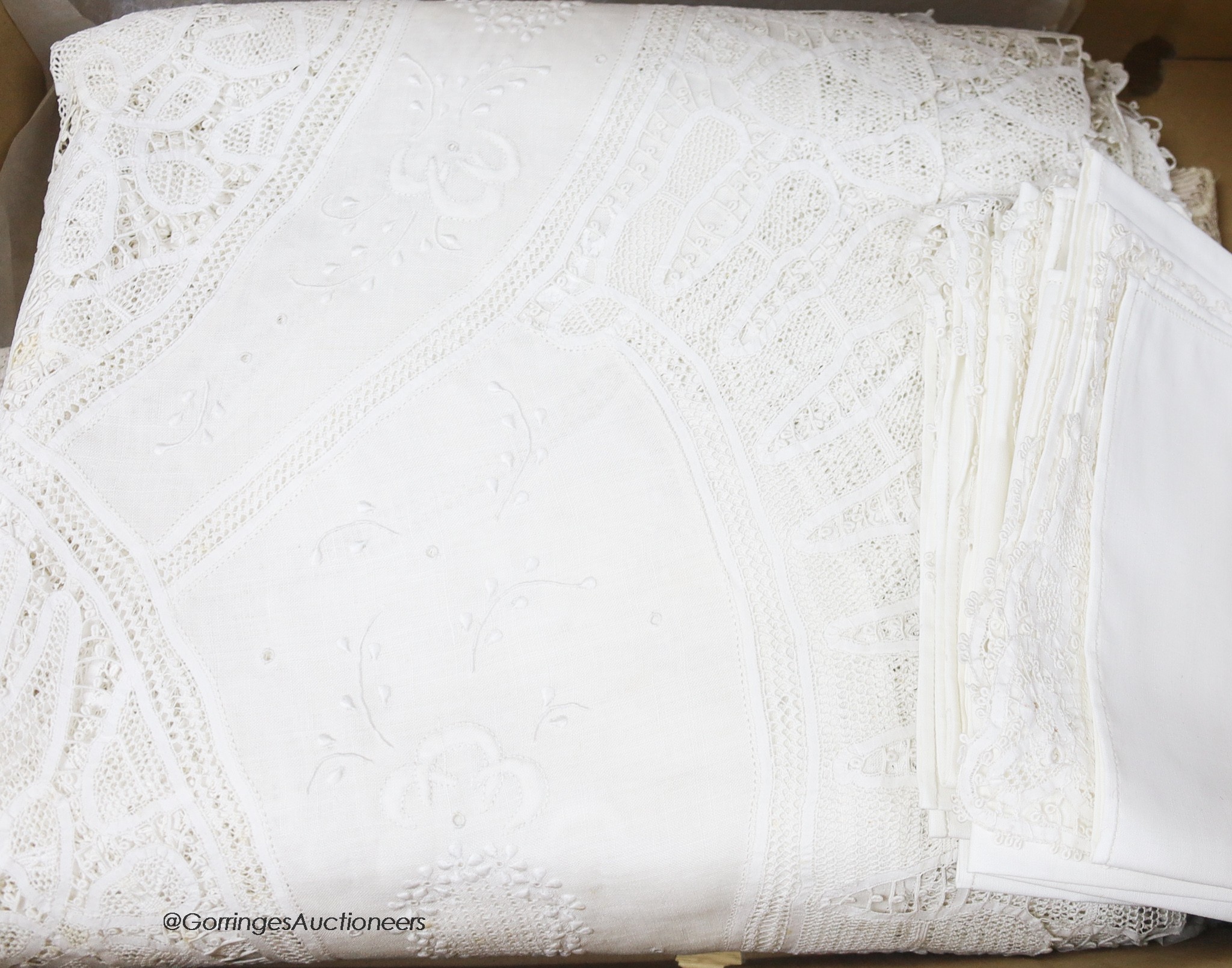 A finely worded tapelace and cutwork white tablecloth with matching serviettes and a similar ecru table cover
